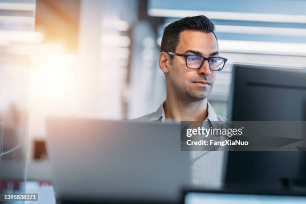 mature caucasian man working on laptop in technology office - job glasses stockfoto's en -beelden