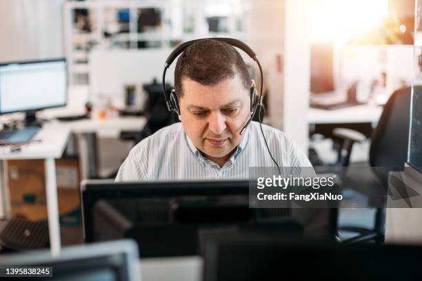middle eastern businessman working in office computer terminal with headset - eastern europe bildbanksfoton och bilder