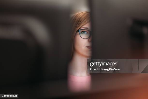 woman peeking through computer monitors in office - nosy woman bildbanksfoton och bilder