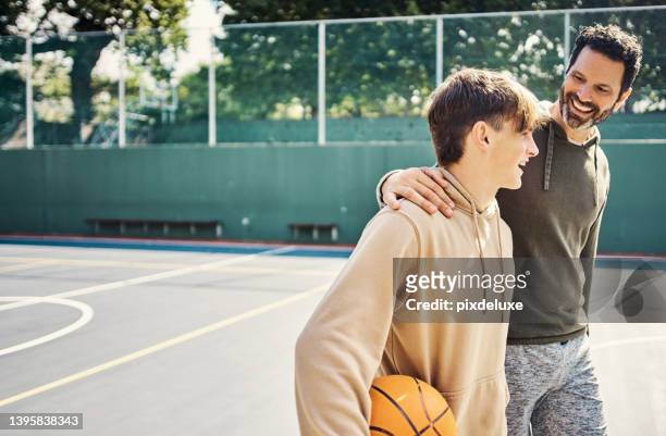 father and son walking after playing a game of basketball. young man and teenage boy having fun, talking and chatting while staying fit, active - father stockfoto's en -beelden