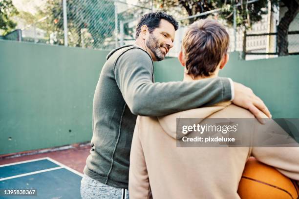 father and son walking after playing a game of basketball. young man and teenage boy having fun, talking and chatting while staying fit, active - end of life care stock pictures, royalty-free photos & images