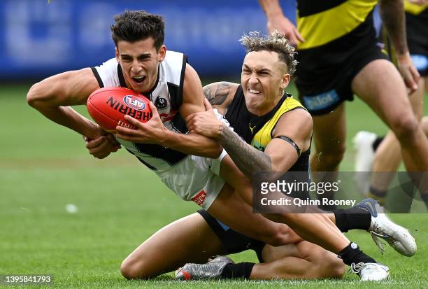 Nick Daicos of the Magpies handballs whilst being tackled by Shai Bolton of the Tigers during the round eight AFL match between the Richmond Tigers...
