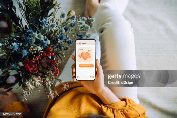 overhead view of young asian woman receiving fresh flower bouquet delivery from her boyfriend and reading the "i love you" text message on smartphone. love and relationship concept. occasions for valentine's day. birthday. dating anniversary - 3 liga fotografías e imágenes de stock