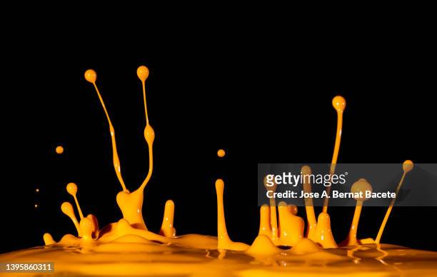 drops and splashes of orange paint in motion on a black background. - watercolour orange and black stockfoto's en -beelden