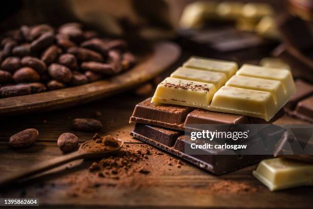 stapel dunkler, milch- und weißer schokoriegel mit kakaobohnen - chocolate pieces stock-fotos und bilder