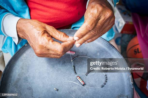 person making handicraft jewelry as souvenirs, antigua - hacer cuentas fotografías e imágenes de stock