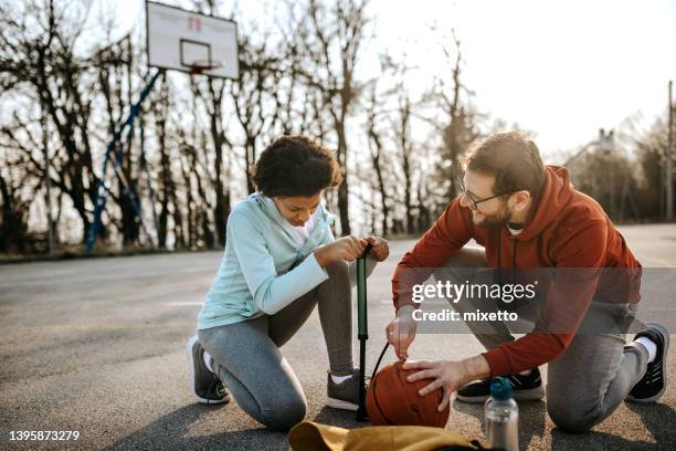 vater mit tochter beim aufblasen von basketball mit pumpe - luftpumpe stock-fotos und bilder