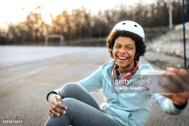 cheerful girl taking selfie with smart phone in public park - children only laughing stock pictures, royalty-free photos & images
