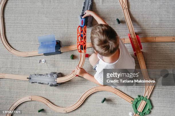 little boy playing iron wooden track at home on the floor. - modelleisenbahn stock-fotos und bilder