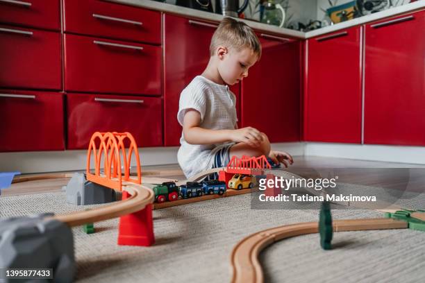 little boy playing iron wooden track at home on the floor. - miniature train stock pictures, royalty-free photos & images