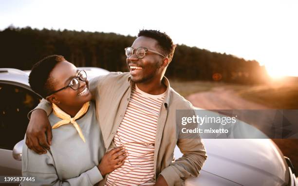 hombre con la mano en el hombro de la novia de pie junto al coche al atardecer - happy couple car fotografías e imágenes de stock