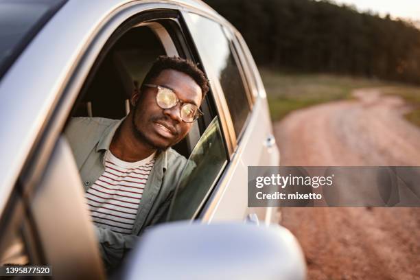 young man peeking through car window at sunset - peeking through window stock pictures, royalty-free photos & images