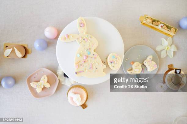 an easter cake and small easter cupcakes shaped like easter bunnies, easter chicks and easter eggs - easter cake stock pictures, royalty-free photos & images