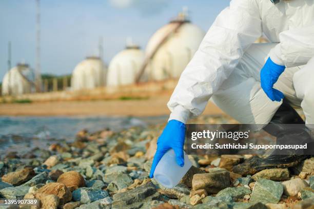 a man wearing protection suit for picking up the trash at the sea. - air pollution monitor stock pictures, royalty-free photos & images