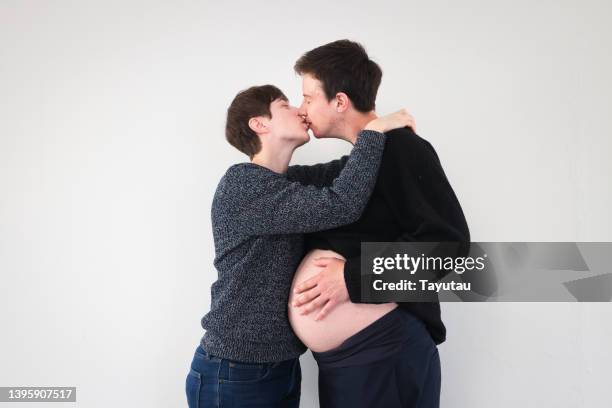 studio portrait of lgbtqia+ couple - belly kissing stock-fotos und bilder