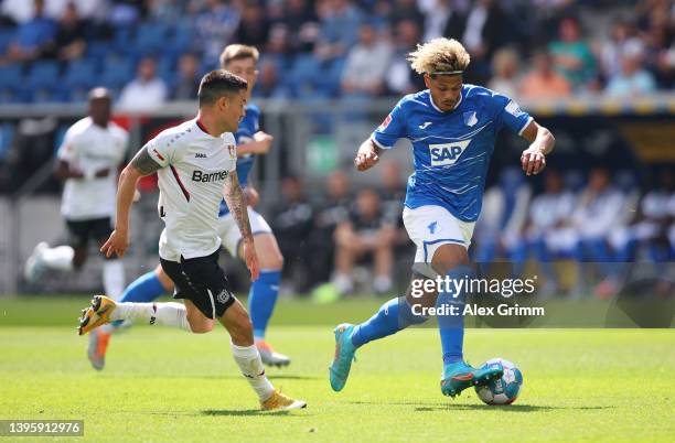 Georginio Rutter of TSG 1899 Hoffenheim is challenged by Charles Aranguiz of Bayer 04 Leverkusen during the Bundesliga match between TSG Hoffenheim...