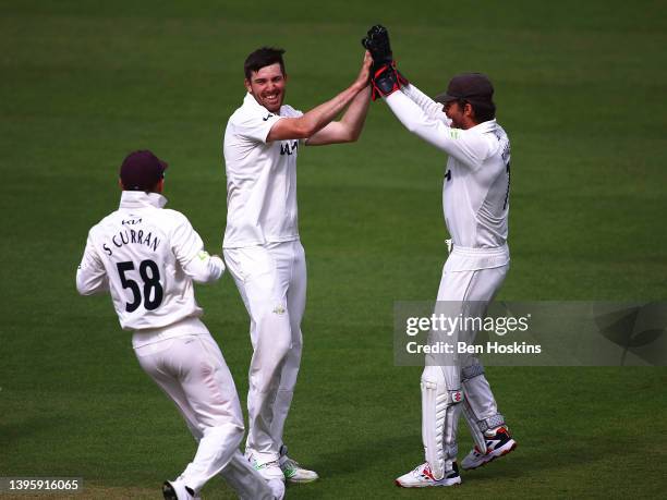 Jamie Overton of Surrey celebrates with team mate Ben Foakes after taking the wicket of Saif Zaib of Northamptonshire during the LV= Insurance County...