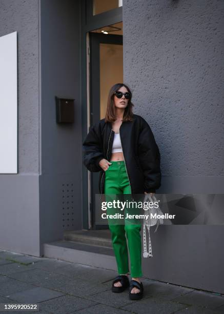 Karla Jenders seen wearing black sunglasses from Prada, a white cropped top from H&M, a black bomber jacket from The Frankie Shop, a green leather...