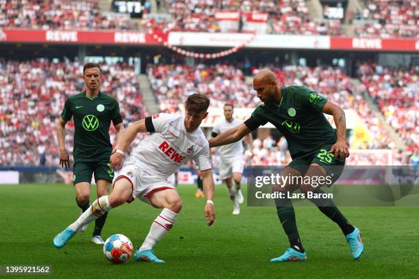 Jan Thielmann of 1.FC Koeln is challenged by John Brooks of VfL Wolfsburg during the Bundesliga match between 1. FC Köln and VfL Wolfsburg at...