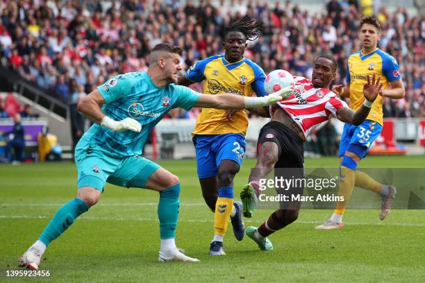 Ivan Toney of Brentford stretches for the ball under pressure from Fraser Forster and Mohammed Salisu of Southampton during the Premier League match...
