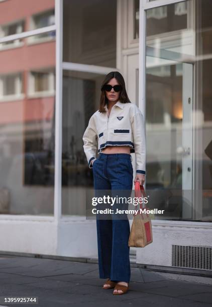Karla Jenders seen wearing black sunglasses from Prada, a white cropped denim jacket from Prada, dark blue wide leg denim jeans from The Frankie...