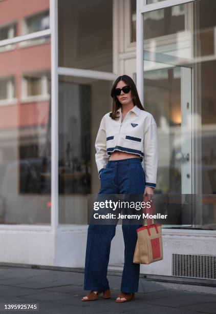 Karla Jenders seen wearing black sunglasses from Prada, a white cropped denim jacket from Prada, dark blue wide leg denim jeans from The Frankie...