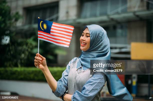 young malaysian woman proudly display her patriotic spirit and solidarity in celebrating the malaysia national day - independent spirit stockfoto's en -beelden