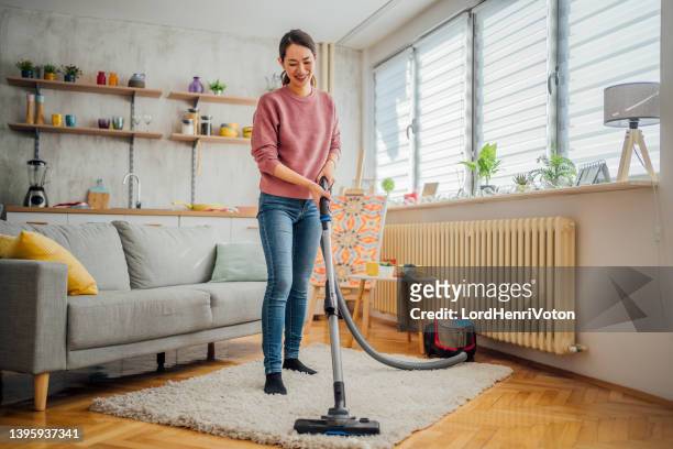 young woman cleaning house with vacuum cleaner - vacuum cleaner woman stockfoto's en -beelden
