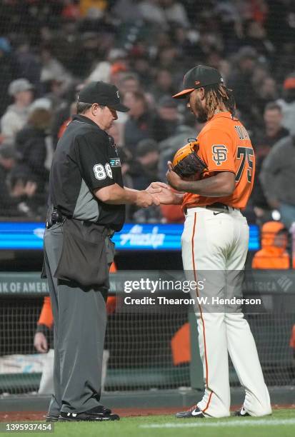 Camilo Doval of the San Francisco Giants has his hand checked by home plate umpire Doug Eddings at the end of the top of the eighth inning against...