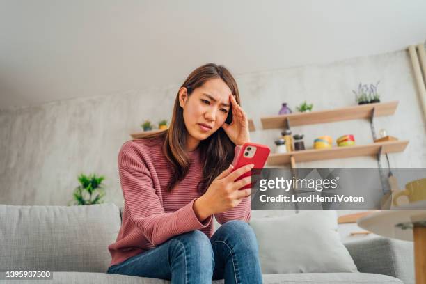 woman looking displeased at mobile phone - female worried mobile imagens e fotografias de stock