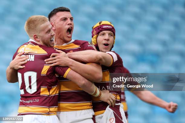 Owen Trout of Huddersfield Giants celebrates with teammates Oliver Wilson and Theo Fages after scoring their side's fourth try during the Betfred...