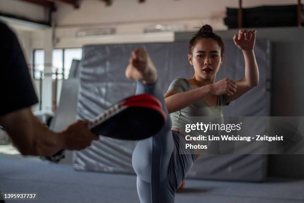 asian chinese girl practising kickboxing with instructor in a gym - martial arts stock pictures, royalty-free photos & images