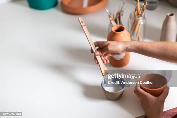 ceramist painting a clay vase in an atelier - painting pottery stock pictures, royalty-free photos & images