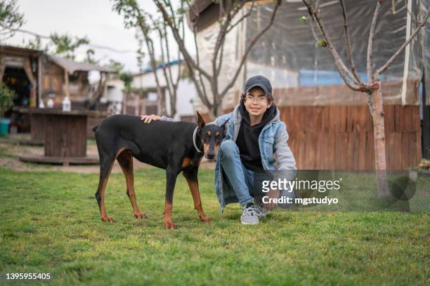 teenage boy playing with his dog in backyard - white doberman pinscher stock pictures, royalty-free photos & images
