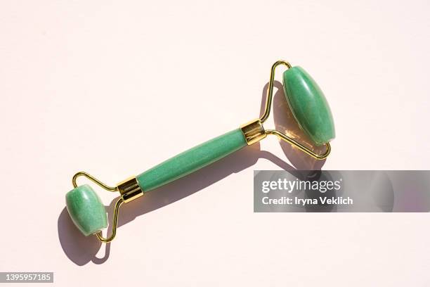 routine step for healthy face skin care and facial massage with green quartz facial jade roller on pastel pink beige colour background. - jade stock pictures, royalty-free photos & images