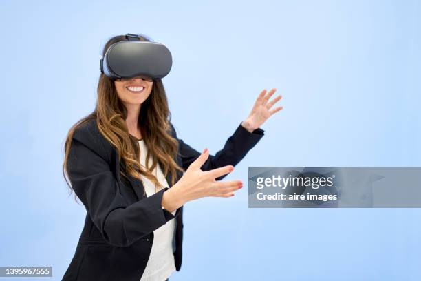 business woman smiles gesturing while wearing virtual reality simulator eyeglasses - vr goggles business stockfoto's en -beelden