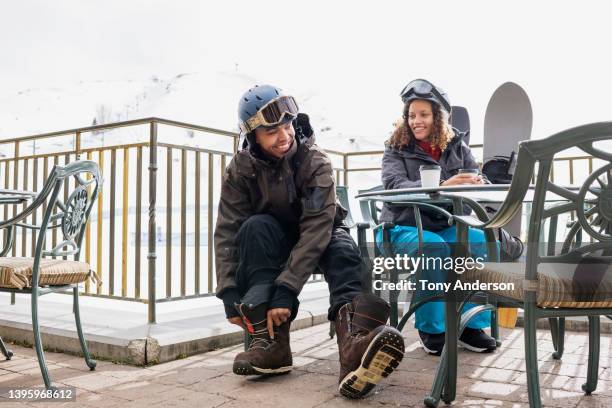 young couple seated at outdoor dining area at ski resort - après ski stockfoto's en -beelden