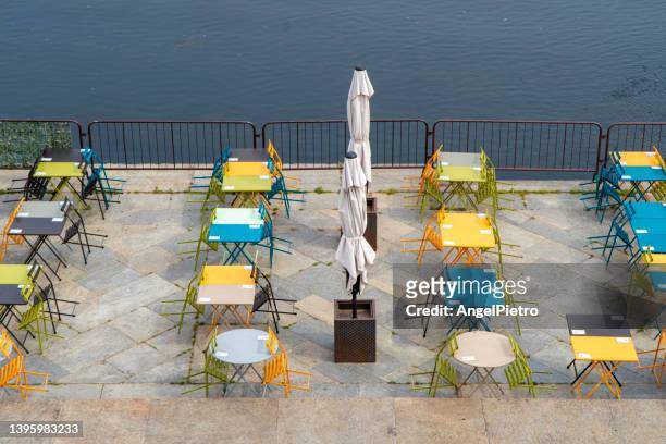 colored chairs and tables to take a drink close the river. - turín stock-fotos und bilder