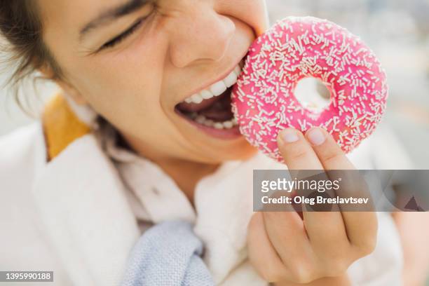 overweight hungry woman biting donut close up. concept of unhealthy fast food eating - fat people eating donuts - fotografias e filmes do acervo