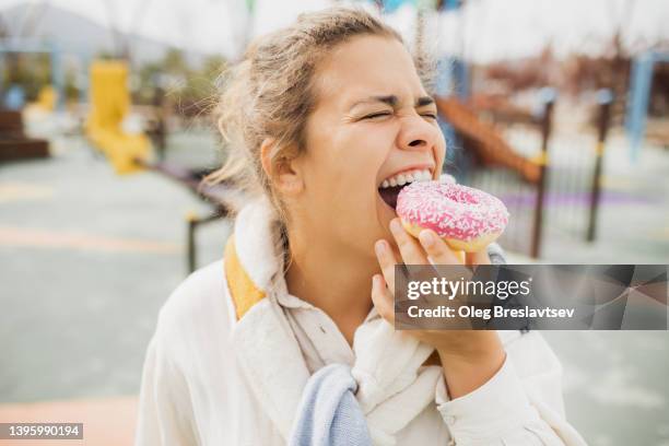 overweight happy woman biting donut close up. concept of unhealthy fast food eating. - fat people eating donuts - fotografias e filmes do acervo