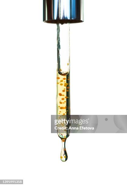 drops of face serum with yellow and orange particles dripping from glass pipette on white background. concept of beauty procedures and body care. polyglutamic acid is a new hyaluronic acid. macro photography - oil macro stock pictures, royalty-free photos & images