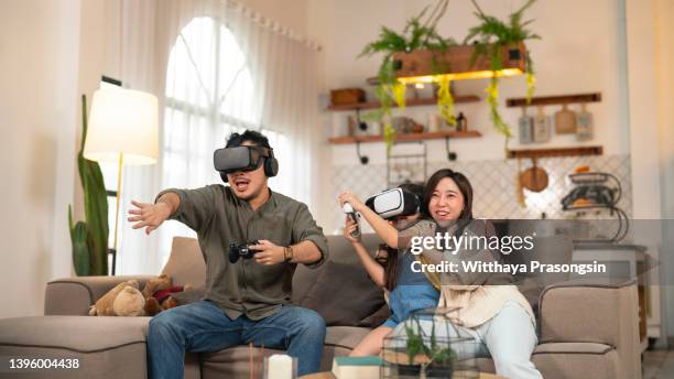 happy asian family at home on living room sofa having fun while they are looking mother and father playing games using virtual reality headset vr in living room at home. - familie technologie virtuell stock-fotos und bilder