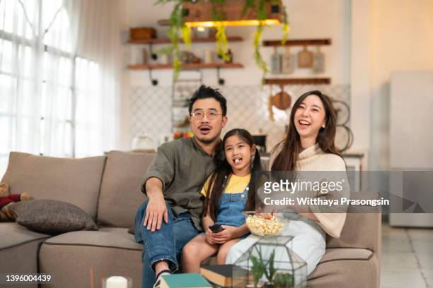 family watching tv and eating popcorn at home - asian cinema bildbanksfoton och bilder