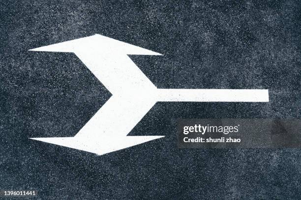 high angle view of arrow symbol on road - links platz stock-fotos und bilder