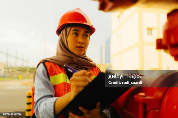 porträt der jungen schönen ingenieurin, die im fabrikgebäude arbeitet - indonesia women stock-fotos und bilder
