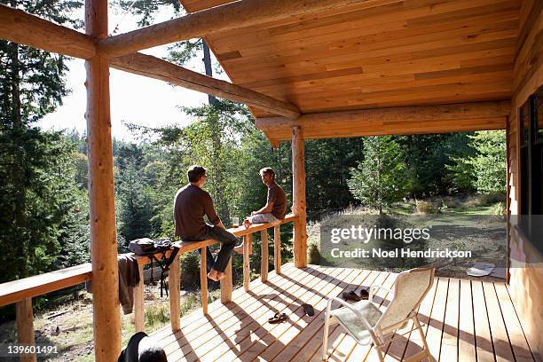 two friends hang out on a cabin patio - log cabin foto e immagini stock