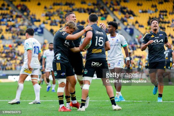 Joshua Moorby of the Hurricanes celebrates with TJ Perenara and Aidan Morgan after scoring a try during the round 12 Super Rugby Pacific match...