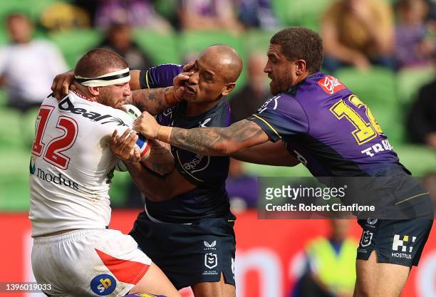 Josh McGuire of the Dragons is challenged by Felise Kaufusi and Kenneath Bromwich of the Storm during the round nine NRL match between the Melbourne...