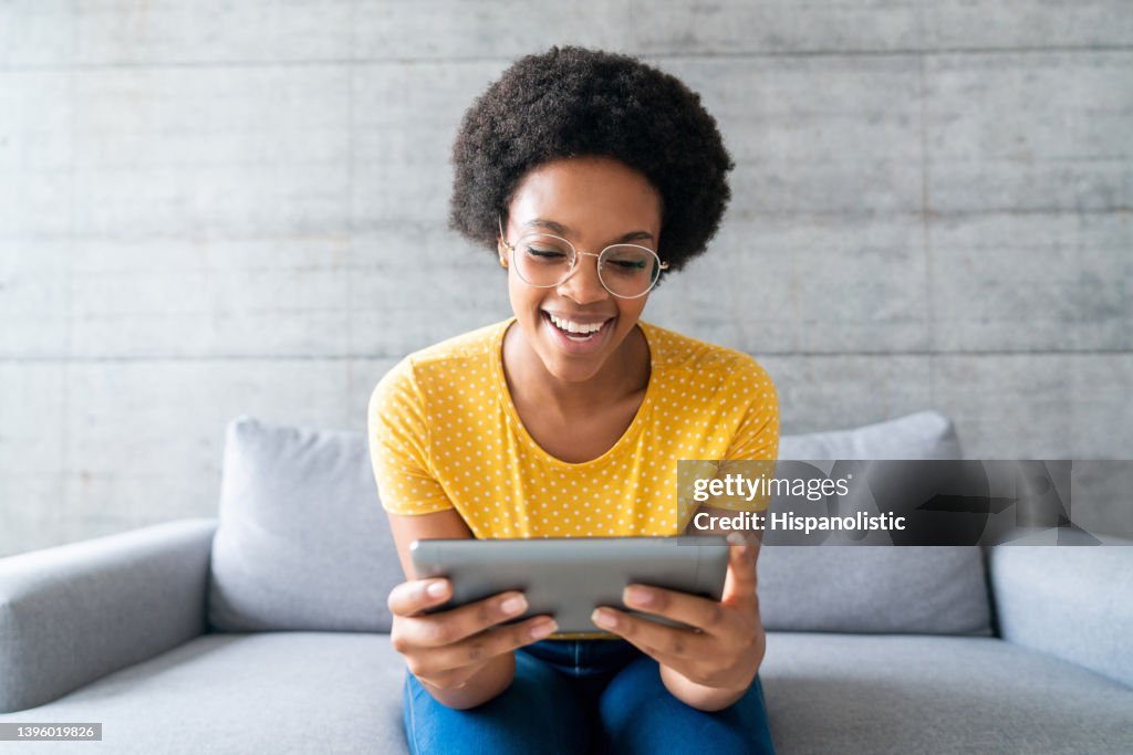 Glückliche Frau zu Hause, die Videos online auf einem Tablet ansieht