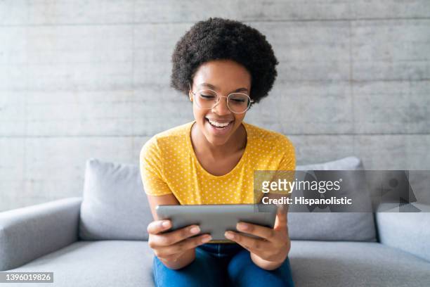 happy woman at home watching videos online on a tablet - watching stock pictures, royalty-free photos & images